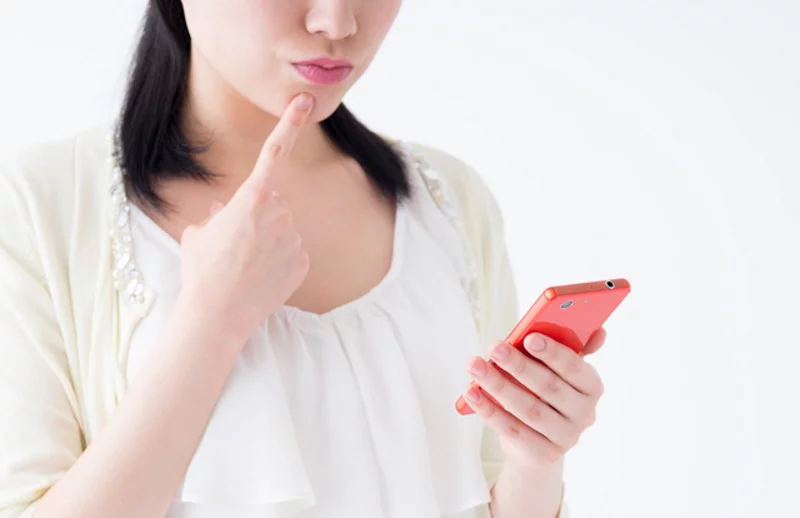スマホを持って疑問を抱える女性